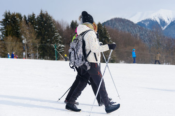 Girls with backpacks walking on snow in the mountains and mountain climbing during the winter holidays.