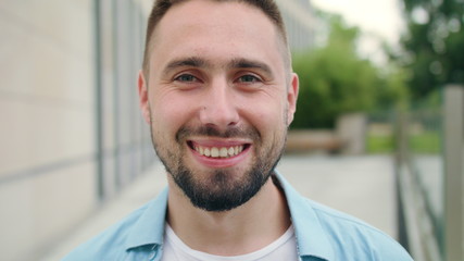 A happy smiling man with a beard in the city street. Close-up shot. Soft focus