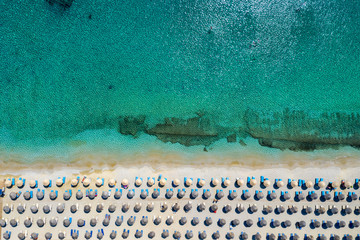 Aufgereihte Sonnenschirme und Sonnenliegen am Strand von Kalafatis auf Mykonos, Griechenland