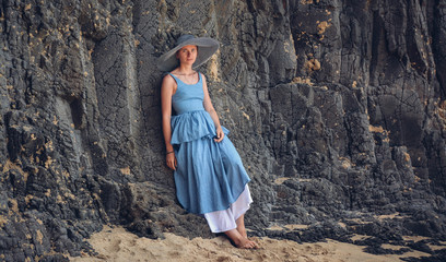 Girl in vintage dress leaning on a wall from a stone