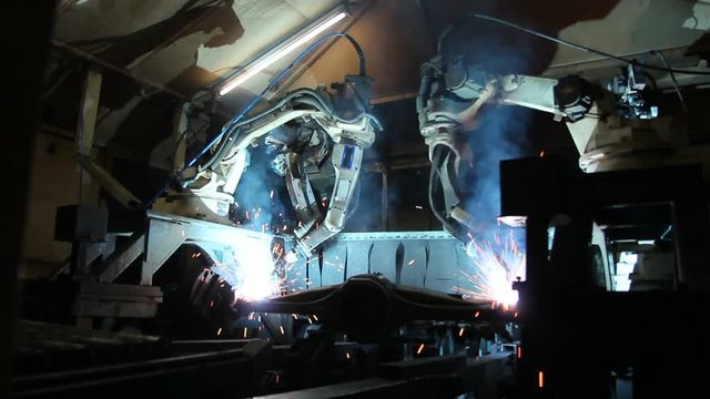 Team industrial robot are movement welding automotive part in factory