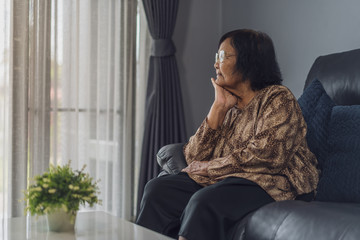 old lonely woman sitting on sofa in living room