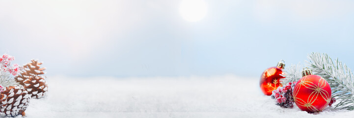 Wide panorama banner design image with festive Christmas decoration ornaments in winter landscape with tree cones and snow in background