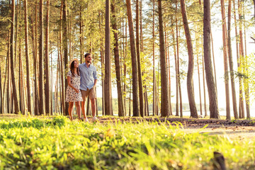 Young couple in love walking in the autumn park holding hands looking in the sunset.