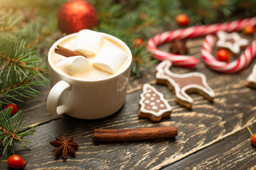 Obraz na płótnie Canvas Winter warming sweet drink hot latte with marshmallows and cocoa in a mug with a Christmas holiday cinnamon on a wooden background, selective focus