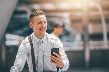 Attractive Smart Businessman Using Smartphone with Smile on Urban Background - Business and Lifestyle Concept