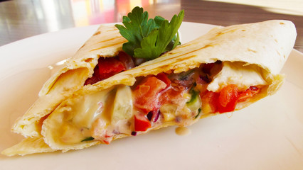 Fresh vegetables in pita bread on a white plate.