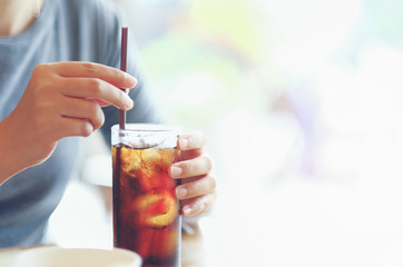 closeup woman Hand holding glass of cola drink in restaurant background, Woman hand glass soft...