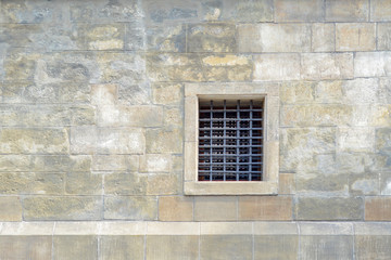 Fototapeta na wymiar The old wall of stone blocks with a lattice window