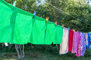 Green cloths drying on a line in  the sun, no people.