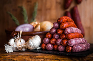 Still life photo of white & red spicy sausages in triangle piramid next to garlic in traditional kitchen onion isolated