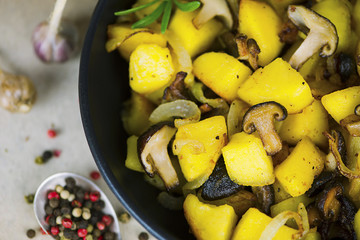 fried potatoes with Japanese shiitake mushrooms and onions in a frying pan