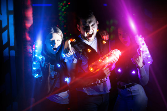 Young people with laser pistols in bright beams