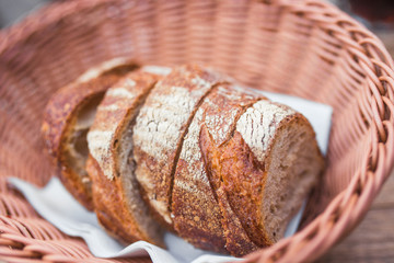 Slices rolls of white ,sourdough rye whole wheat brown dark cereal natural bread handmade at bakery with flour barley in wicker basket, in grocery baking cafe table. Concept of organic gourmet diet   