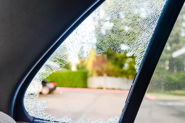 Outside close-up view broken passenger window car smashed by thief or accident. Damaged glass from...