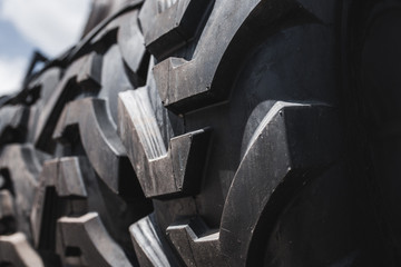 Big set of black huge big truck, tractor or bulldozer loader wheel close-up on stand, shop selling tyres for farming and big vehicles Construction machinery. Lot of pattern tread of Off-road tires. 