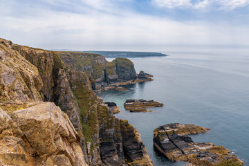 Obraz premium Cliffs on the Anglesey coast near South Stack Lighthouse with Abraham's Bosom in the background, Gwynedd, Wales, UK