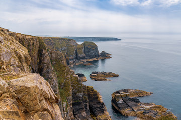 Cliffs on the Anglesey coast near South Stack Lighthouse with Abraham's Bosom in the background, Gwynedd, Wales, UK