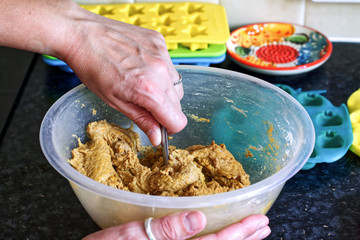 Making home made dog biscuits in brightly coloured plastic molds, hand holding kitchen implement