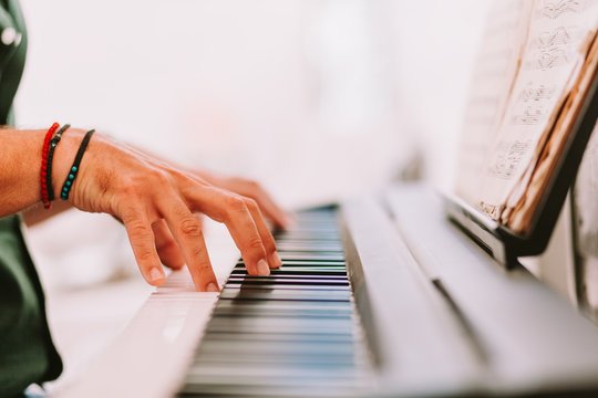 Male hands playing piano at home studio
