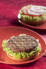 Beef Burger with bell pepper and lettuce with cherry red and yellow tomato on Red background 