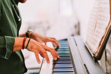 Male hands playing piano at home studio