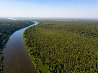 Ob river flows through the taiga. River landscape, beautiful sky reflection in water. Vasyugan Swamp from aerial view. Tomsk region, Siberia, Russia