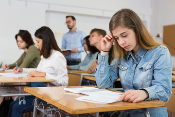 Fototapeta premium Smiling schoolgirl is learning and answering the question on paper