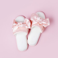 Stylid female slippers with bow on pale pink  background. Flat lay, top view