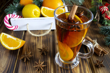 Mulled wine, the tray with oranges and lemon on the brown wooden background.