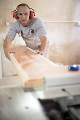 Carpenter working on woodworking machines in carpentry shop