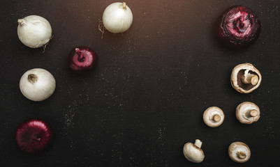 Composition of mushrooms and onion on black stone background, top view