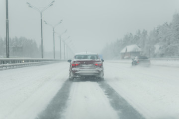 Car with lights on a snow covered road.