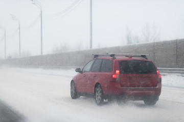 Fototapeta na wymiar Car with lights on a snow covered road.