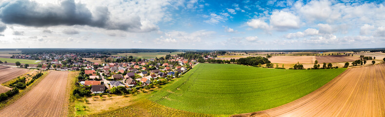 Fototapeta na wymiar Aerial view of a small village in northern Germany with large arable land at the edge of the village, Panorama in high resolution.