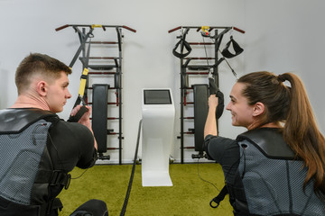 Back view of two athletes in EMS vests doing suspension training