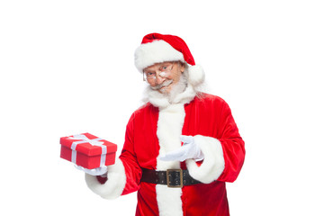 Christmas. Smiling Santa Claus in white gloves is holding a gift red box with a bow. Pointing at the gift. Isolated on white background.