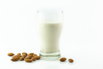 Almond milk in glass with almonds seed on white background