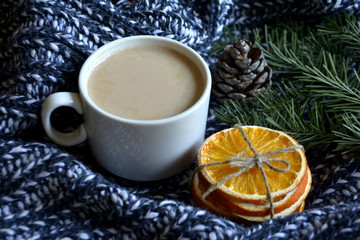 Obraz na płótnie Canvas Cup of coffee with milk pine branches dried oranges on a knitted blanket