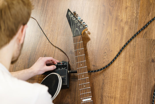 Man adjusting guitar effects pedal