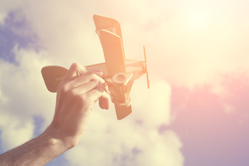 Toy airplane in hand - a symbol of travel and dreams. Instagram effect, toned photo filter