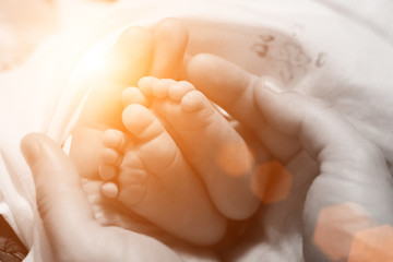 Newborn's legs in father's hands, with instagram effect