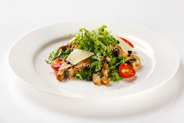 Plate with fried chicken meat served with salad, tomato, parmesan and sauce isolated at white background.