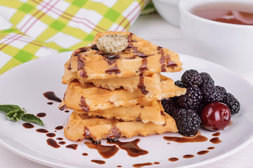 Delicious sweet Belgian waffles in the form of hearts with chocolate and berries close-up