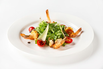 Plate of delicious salad with fried prawns, tomato, parmesan and green isolated at white background.