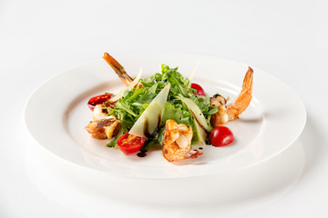 Plate of delicious salad with fried prawns, tomato, parmesan and green isolated at white background.