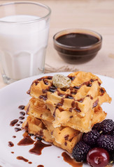 Delicious sweet Belgian waffles in the form of hearts with chocolate and berries with a glass of milk. breakfast. on a natural wooden background