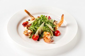 Plate of delicious salad with fried prawns, tomato, parmesan and green isolated at white background.
