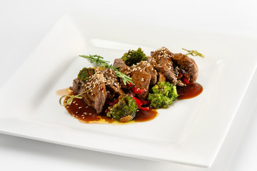 Closeup plate of delicious beef meat with brocolli, pepper and sauce isolated at white background.