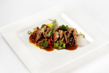 Closeup plate of delicious beef meat with brocolli, pepper and sauce isolated at white background.
